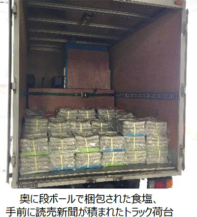奥に段ボールで梱包された食塩、手前に読売新聞が積まれたトラック荷台